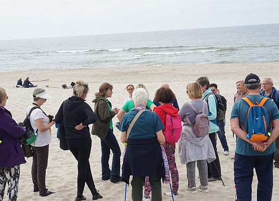Grupa ludzi na plaży dyskutuje o walorach przyrodniczych wydm